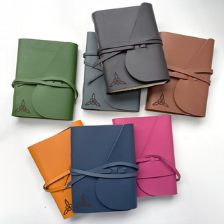 Multiple colourful leather cover journals laid out on table