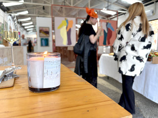 Candle on a table with people in the background at an event set within an art gallery