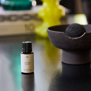 Peppermint orchid essential oil bottle on a reflective surface with a blurred background