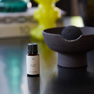 Small bottle of Volcanic Embers diffuser oil on a dark surface with a blurred background